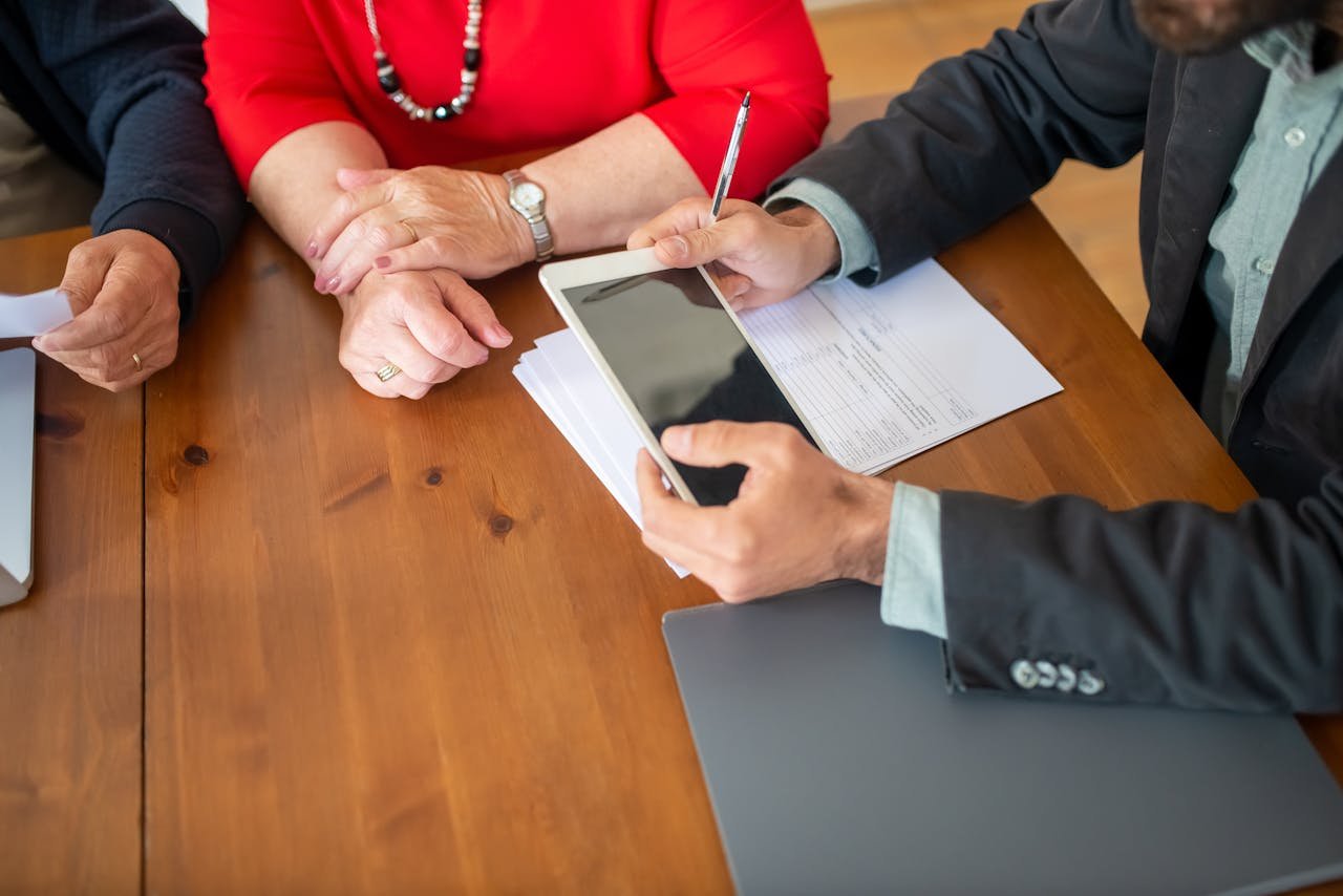 services-01 Business meeting at a wooden table with consultant reviewing documents and using a digital tablet.